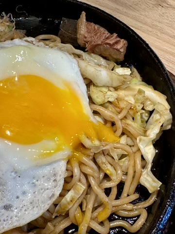 すじコン焼きそばの目玉焼きの黄身が割れたところの写真